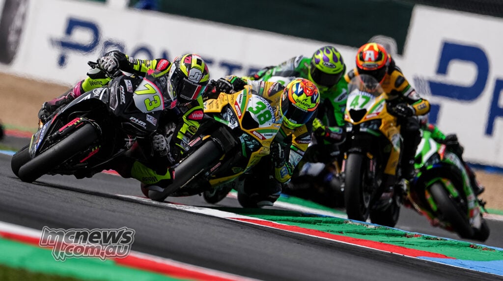 Fenton Seabright on the number 73 Triumph races alongside David Salvador on the number 38 Kawasaki with the pack behind.