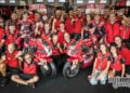 Nicolo Bulega, Iker Lecuona and the Aruba.it Racing Ducati team celebrate around two red Panigale V4 R race bikes.