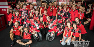 Nicolo Bulega, Iker Lecuona and the Aruba.it Racing Ducati team celebrate around two red Panigale V4 R race bikes.