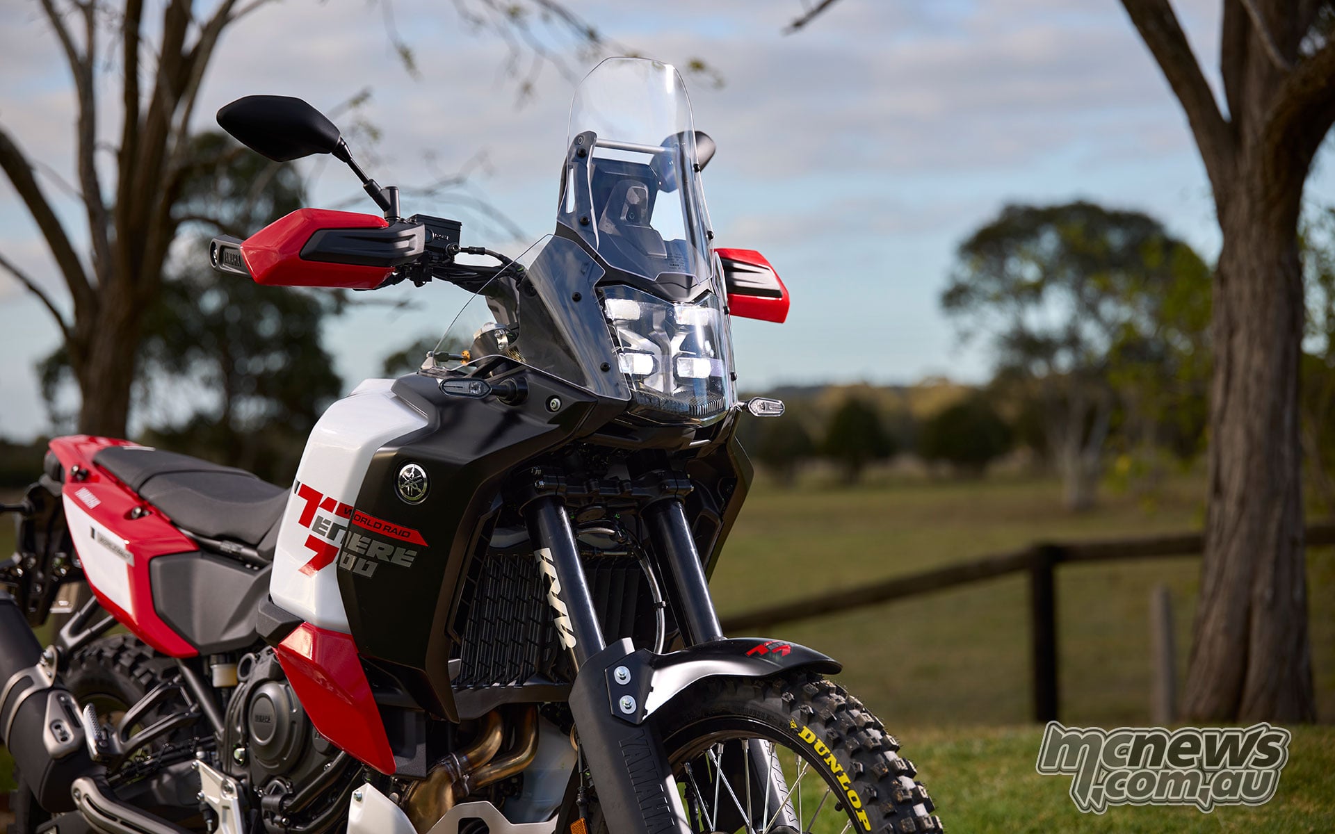 Close front-right view of a red and white Yamaha Ténéré 700 World Raid with its headlights illuminated.