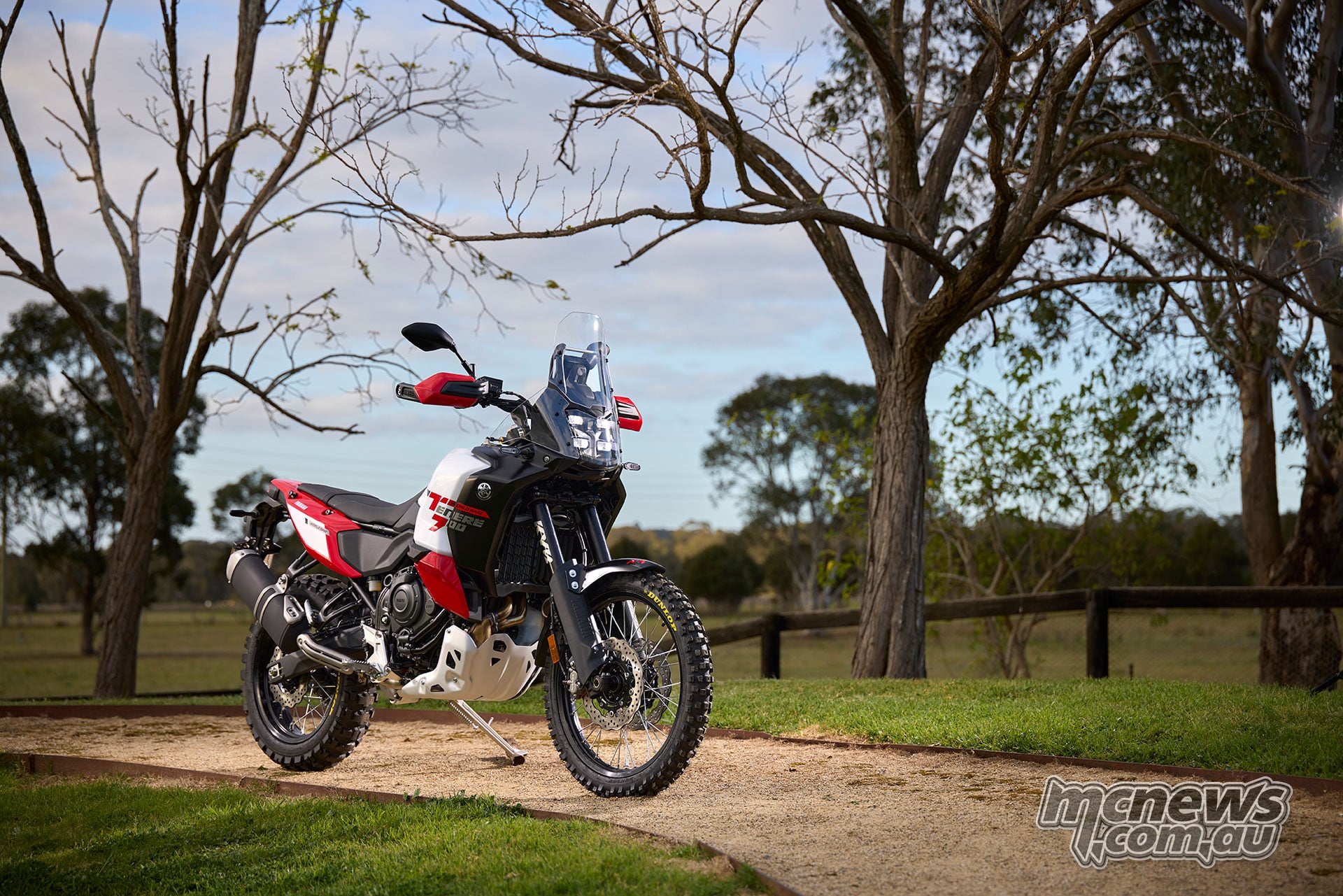 Red, white and black 2026 Yamaha Ténéré 700 World Raid parked beneath trees, viewed from the front right.