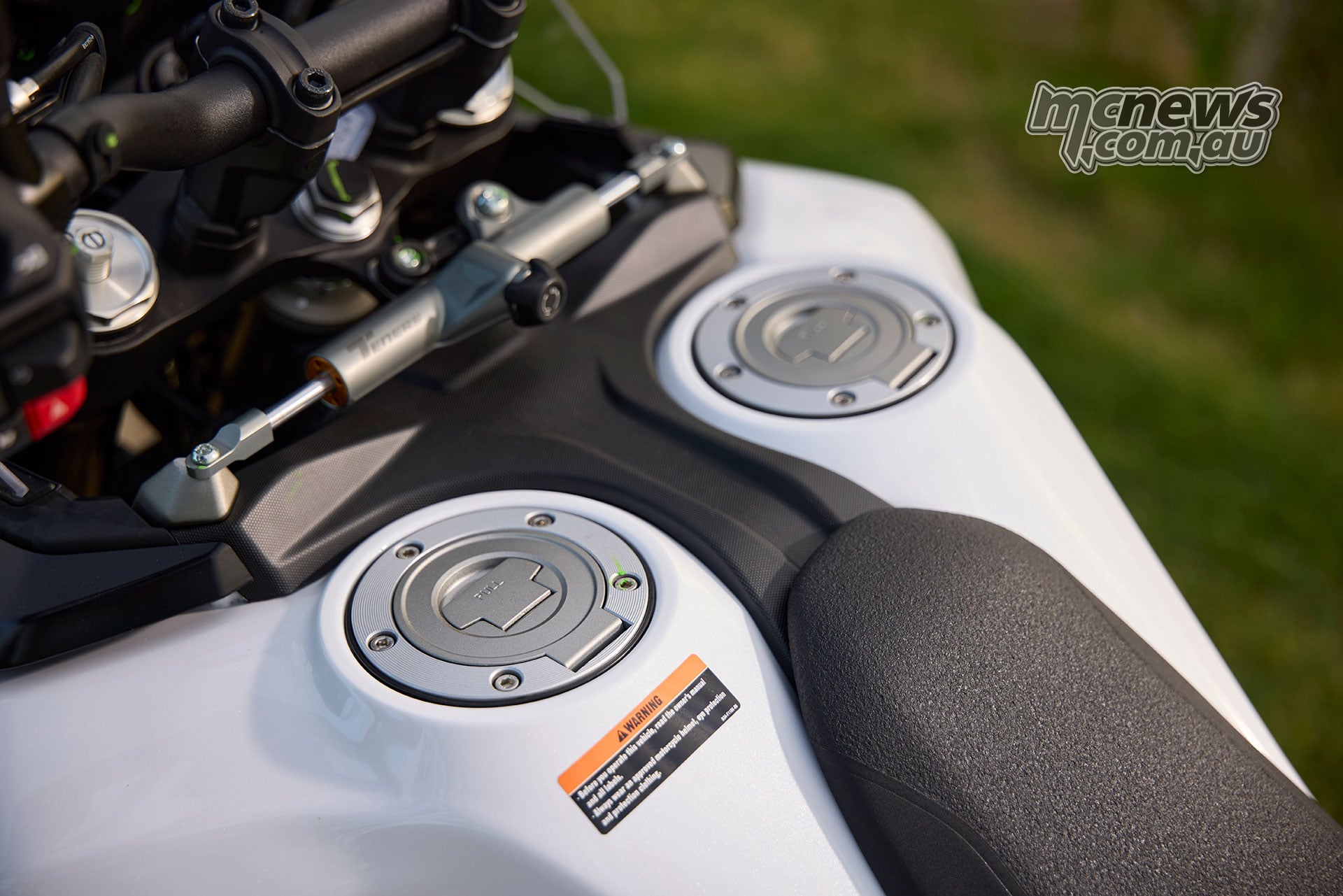 View down over the World Raid’s two fuel filler caps, white tanks and the front of its black seat.
