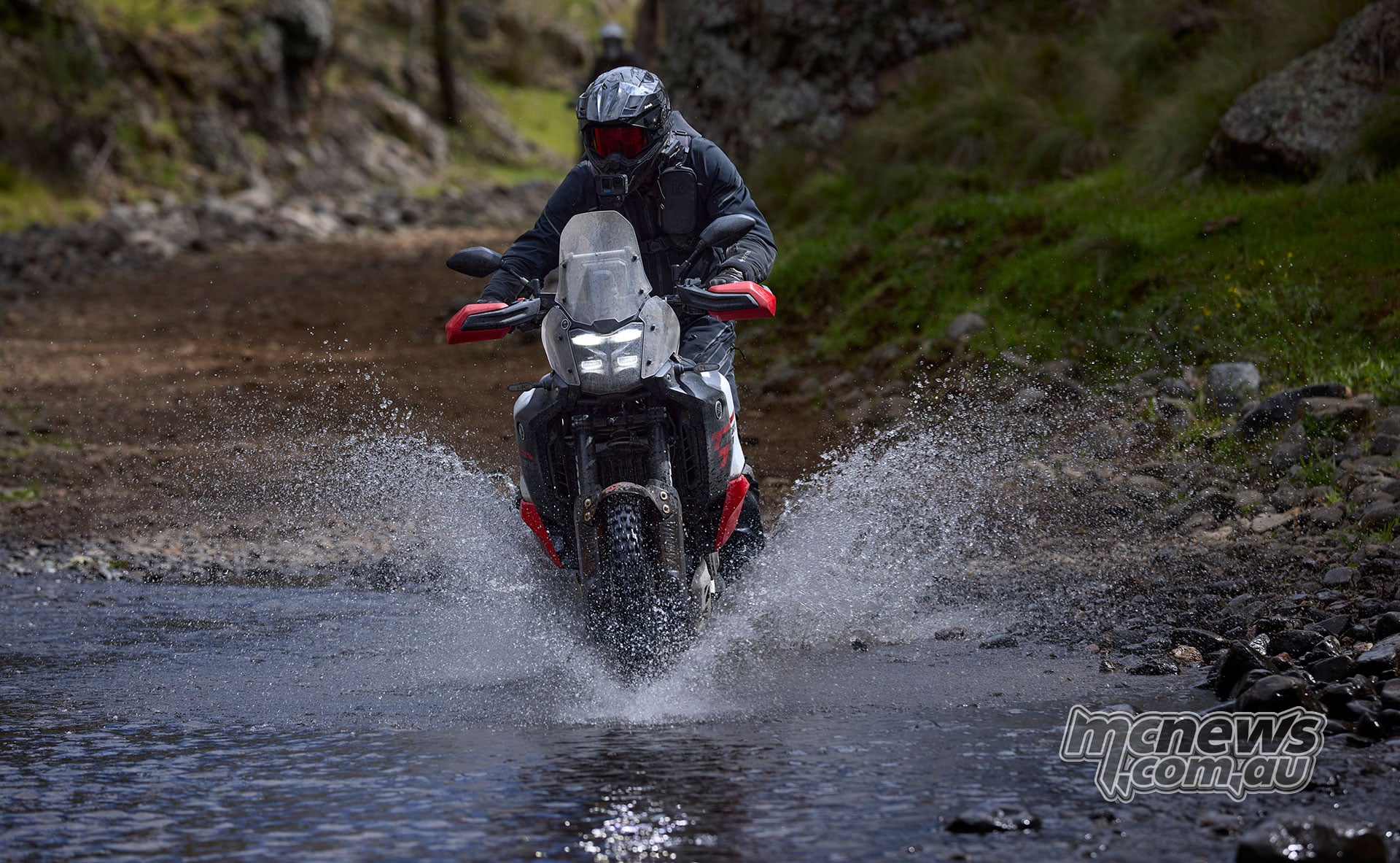 Front view of a Yamaha Ténéré 700 World Raid splashing through a rocky creek crossing.