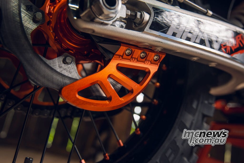 Close-up of the orange rear brake-disc guard and solid rotor on the 2027 KTM 300 EXC HARDENDURO.