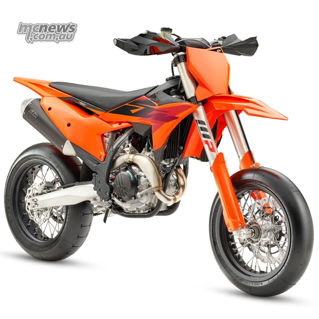 Front three-quarter studio view of the orange 2027 KTM 450 SMR with black handguards and slick tyres
