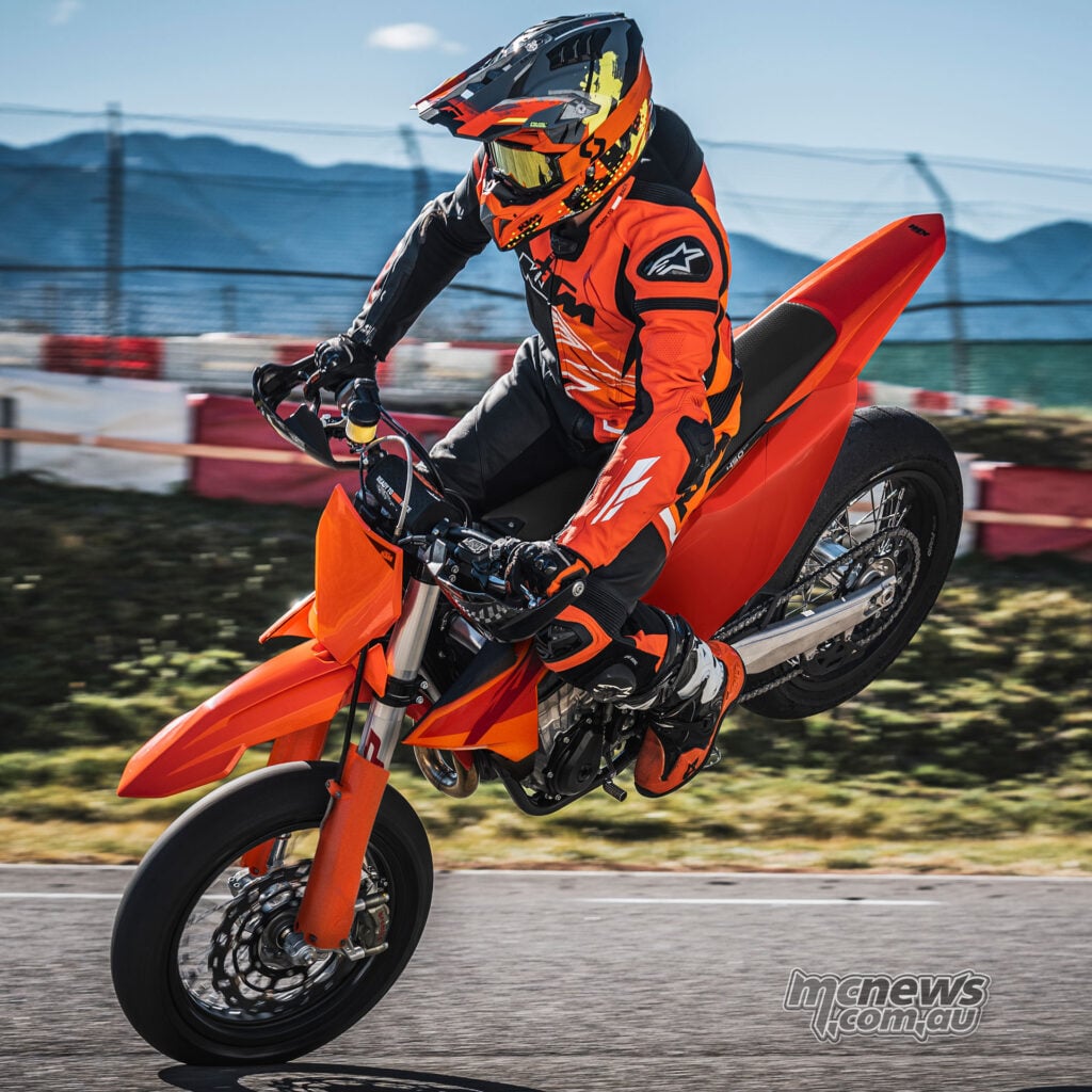 Rider performing a wheelie on the orange 2027 KTM 450 SMR at a Supermoto track