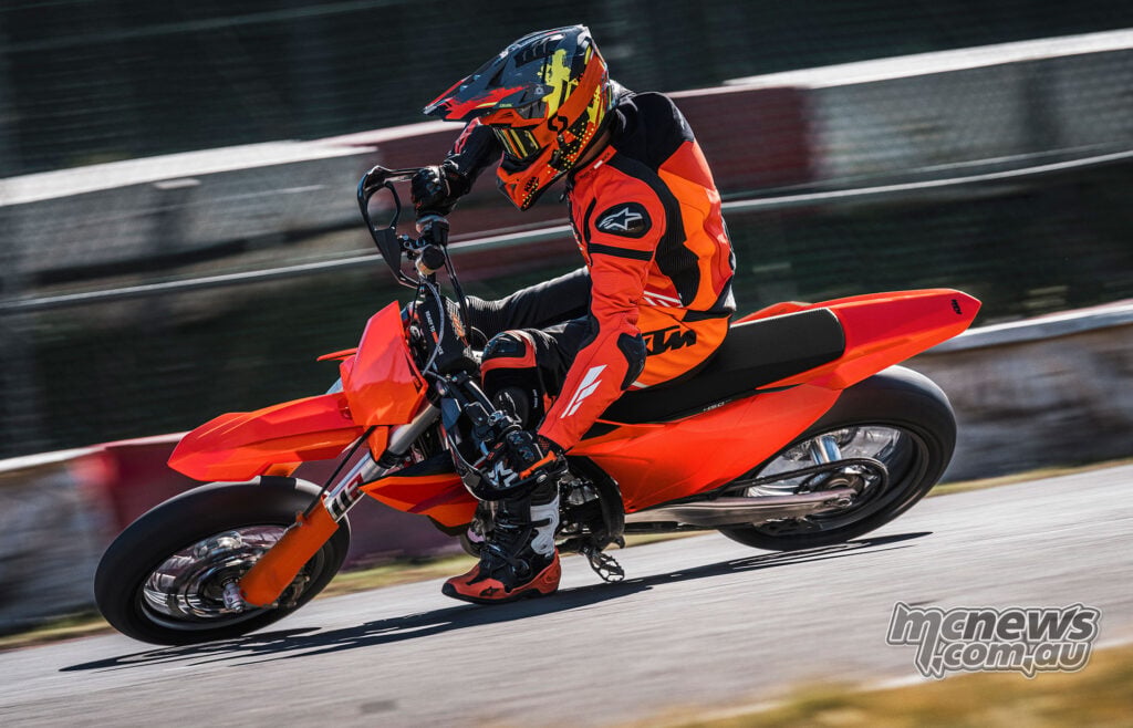 Rider cornering the 2027 KTM 450 SMR on asphalt with motion-blurred barriers behind