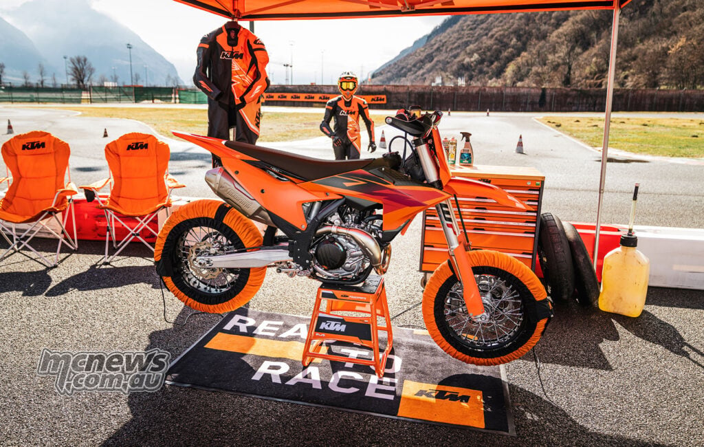 2027 KTM 450 SMR under a KTM paddock awning with tyre warmers, tools and an Akrapovic silencer