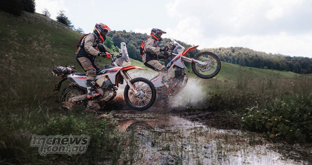 Two 2027 KTM 690 Rally motorcycles riding through a rocky water crossing