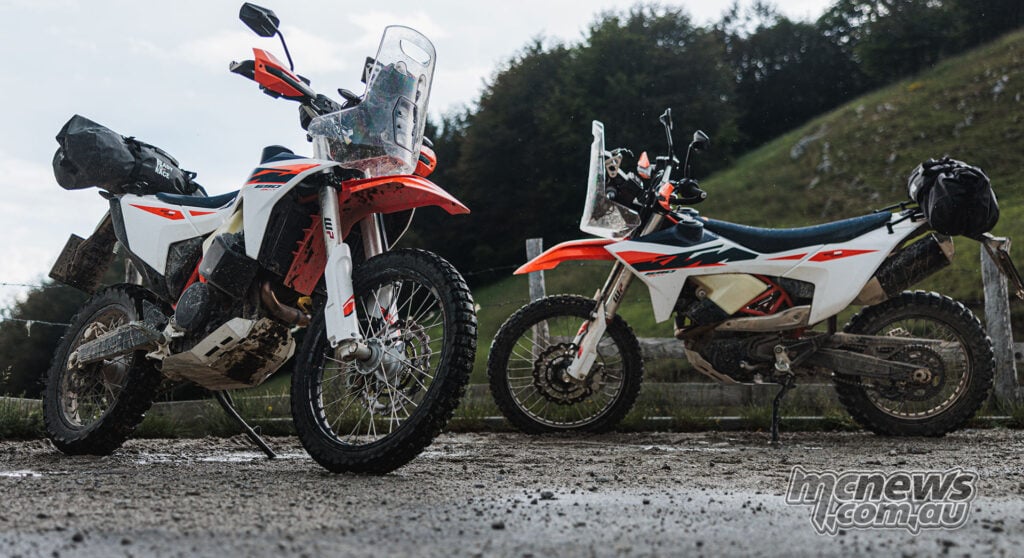 Two luggage-equipped 2027 KTM 690 Rally motorcycles parked during an off-road ride