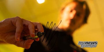 Nicolò Bulega signs a glass panel after being confirmed as a Pertamina Enduro VR46 MotoGP rider for 2027.