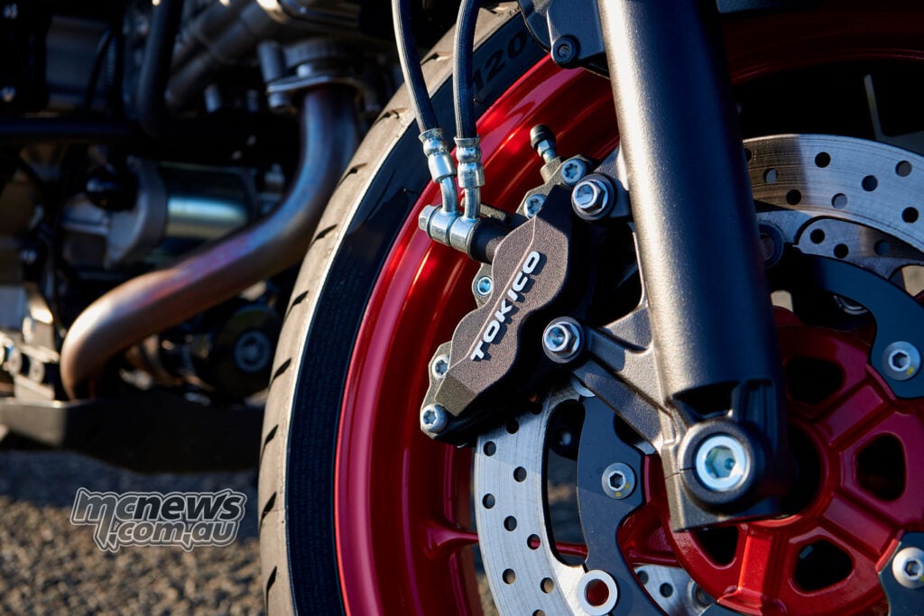 Close-up of a Tokico four-piston front brake calliper and disc on a red Suzuki SV-7GX wheel
