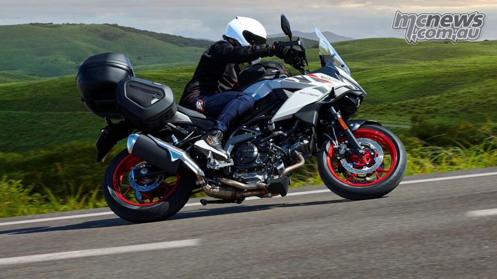 Pearl Matte Greige Suzuki SV-7GX with red wheels and touring luggage being ridden through green hills
