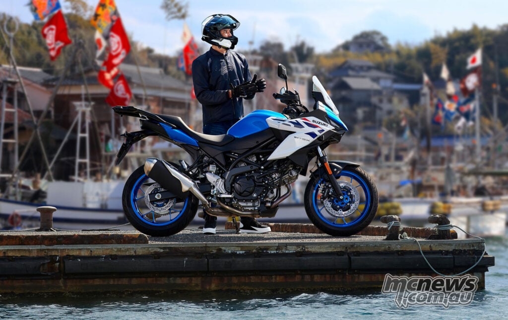 Blue and white Suzuki SV-7GX in side profile on a waterfront wharf with a rider standing behind it