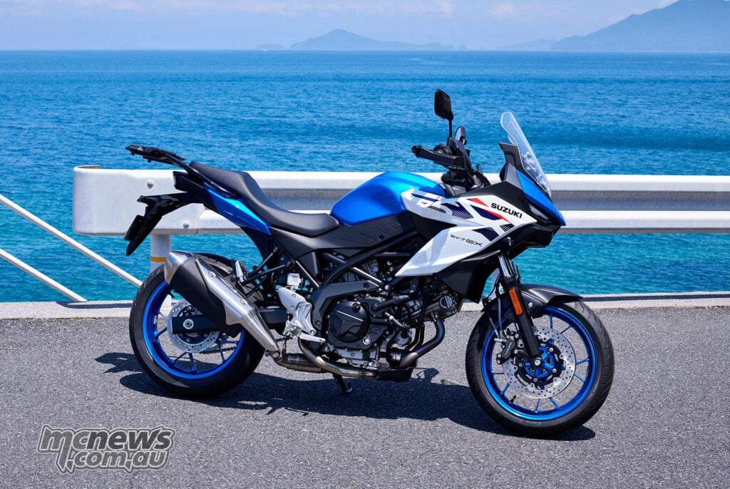Pearl Brilliant White and Metallic Triton Blue 2027 Suzuki SV-7GX in right-side profile beside the sea