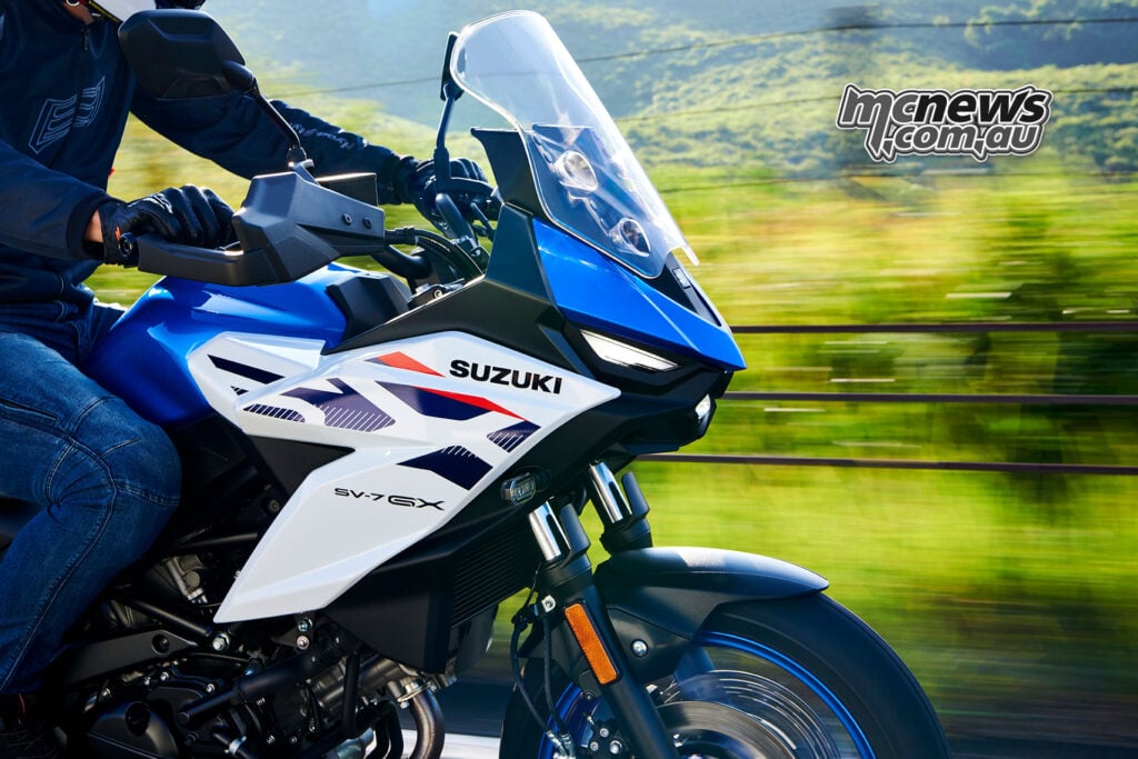 Close side view of a blue and white Suzuki SV-7GX front fairing, windscreen and hand guard while riding