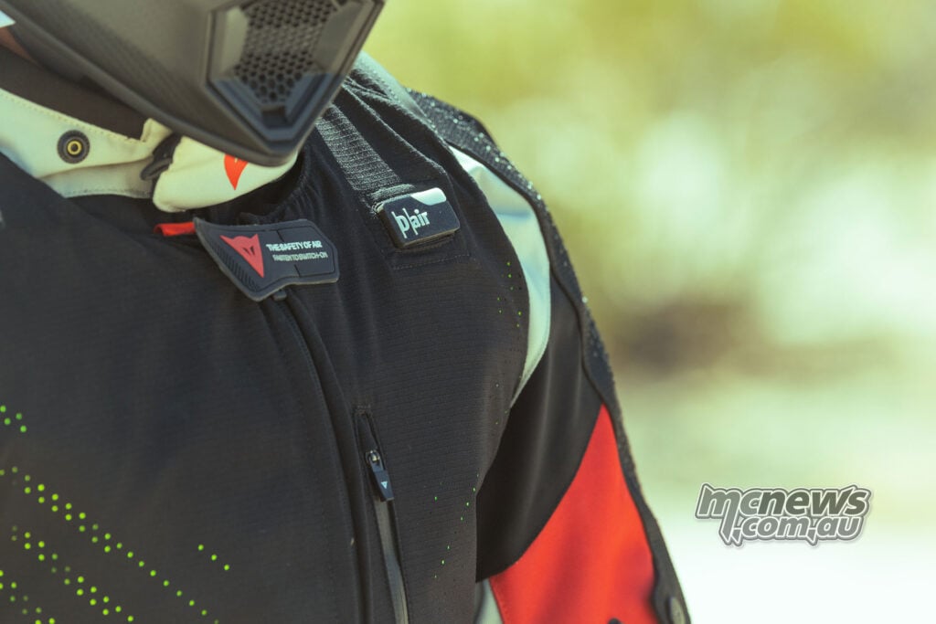 Close-up of the upper chest, fastening tab and shoulder area of a black Dainese Smart Air vest worn over an adventure motorcycle jacket.