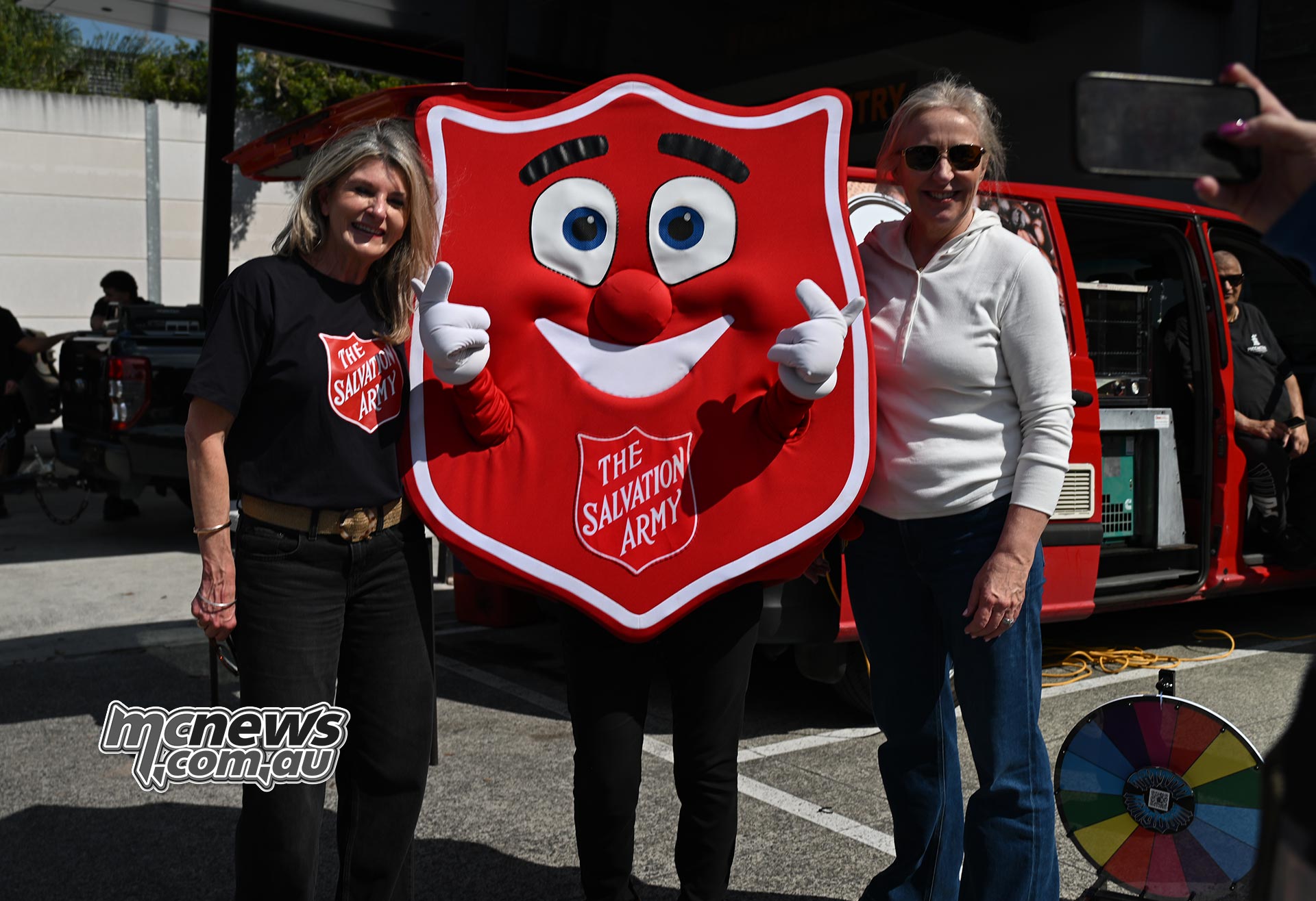 Two supporters posing with The Salvation Army mascot at the 2026 Harley-Davidson United We Ride charity event