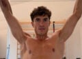 Front view of Marc Márquez training with both arms raised, with surgical scarring and reduced muscle bulk visible on his right arm.
