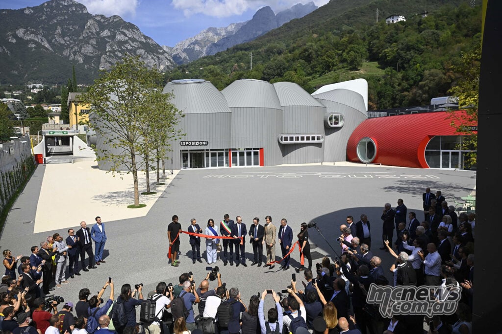 Guests gather around a red ribbon at the opening of Moto Guzzi’s new museum beneath the Mandello mountains.