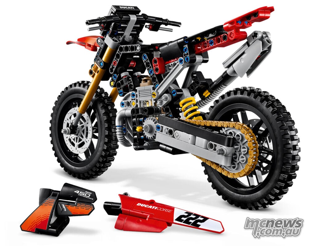 LEGO Technic Ducati Desmo450 MX Factory with its side panels removed, exposing the frame, engine, rear spring and chain drive.