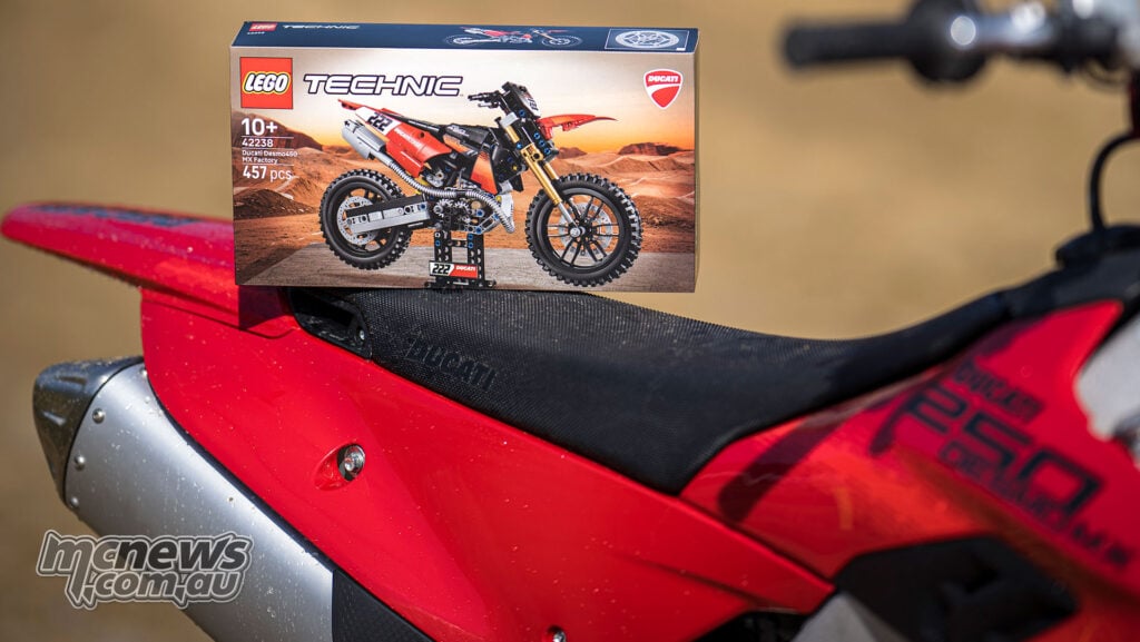 LEGO Technic Ducati Desmo450 MX Factory set 42238 box resting on the seat of a real red Ducati motocross bike.
