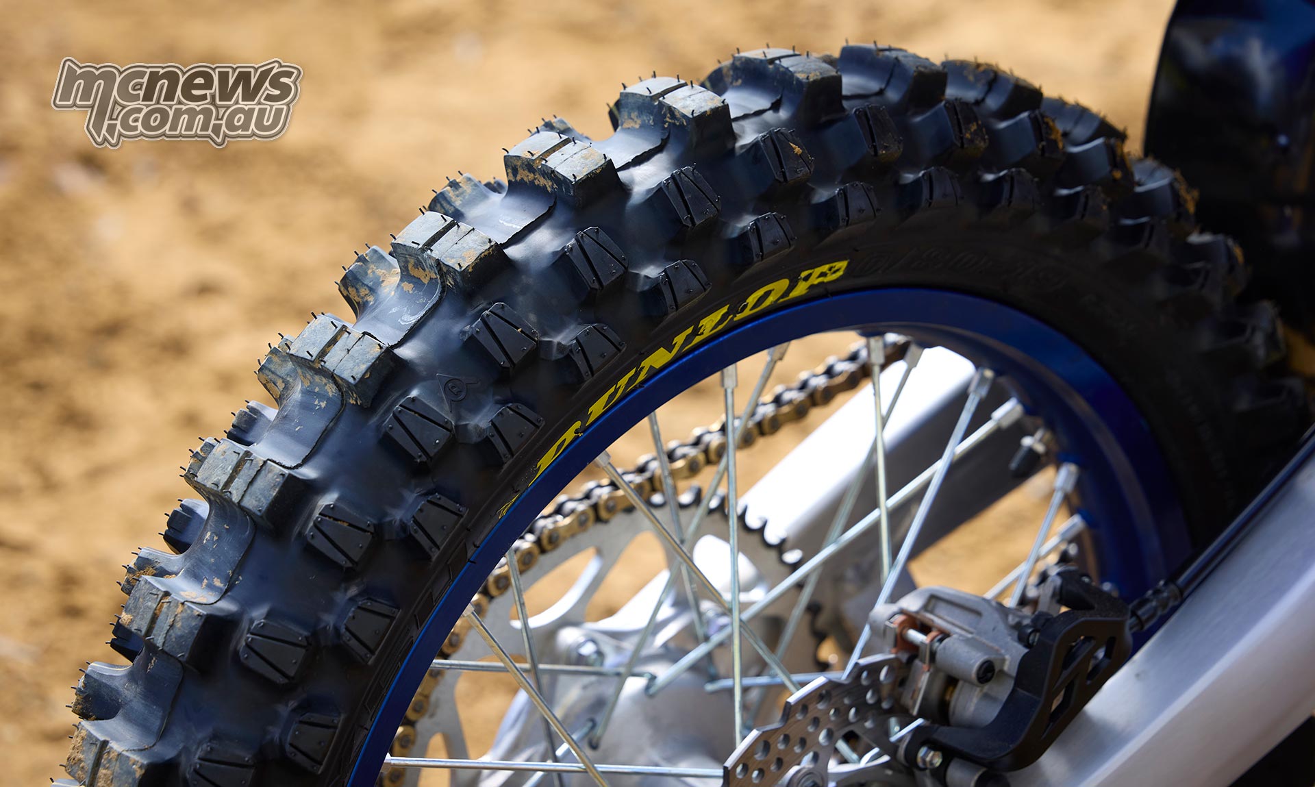 Close-up of a Dunlop Geomax MX54 rear motocross tyre fitted to a blue Yamaha wheel, showing the centre and shoulder tread blocks.