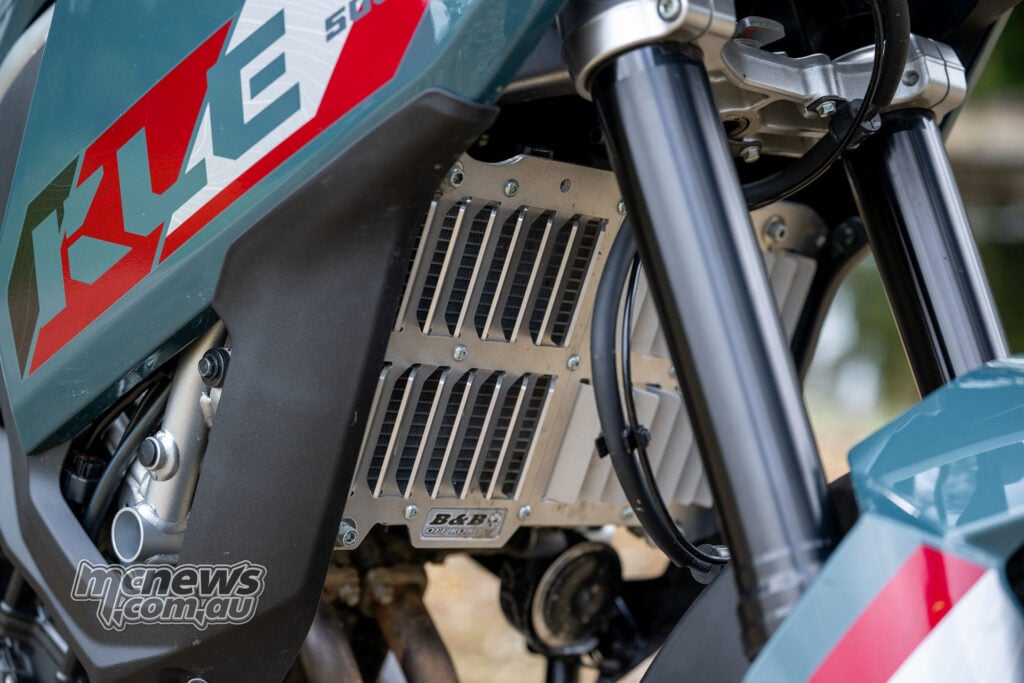 B&B radiator guard mounted behind the Kawasaki KLE500 SE fork legs, beside the blue-green fairing and KLE graphics.