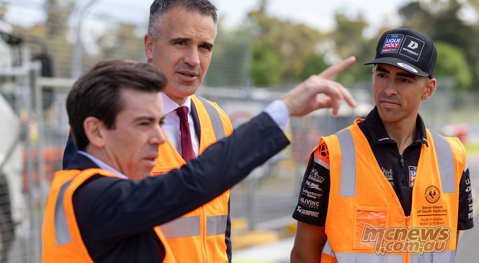 Carlos Ezpeleta points across the Adelaide circuit precinct with Peter Malinauskas and Senna Agius wearing high-visibility vests