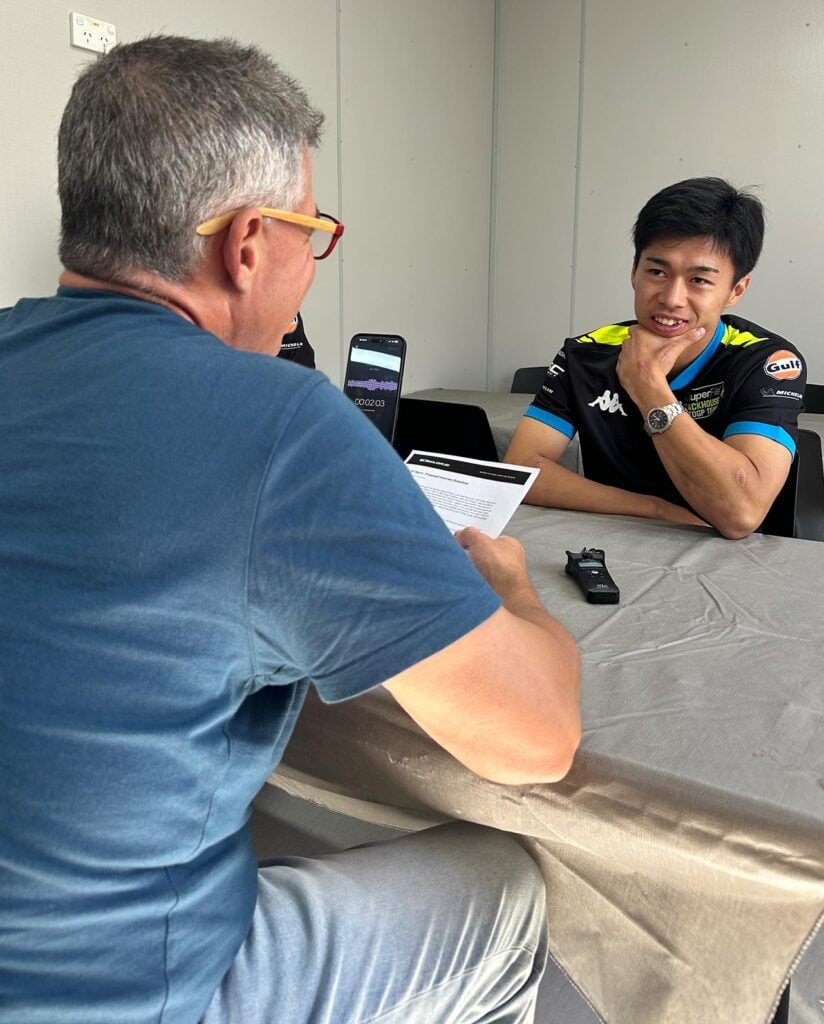 Trevor Hedge, left, interviewing Ai Ogura across a table at Phillip Island, with interview notes and an audio recorder between them.