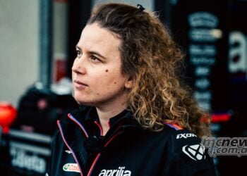Elena De Cia, Aprilia Racing's Strategy and Data Analysis Lead, pictured in profile wearing Aprilia team clothing in the MotoGP paddock.