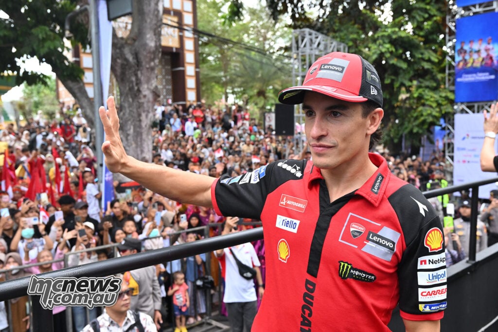 Marc Marquez waves to the crowd in his red Ducati team shirt and cap during the Mandalika parade.
