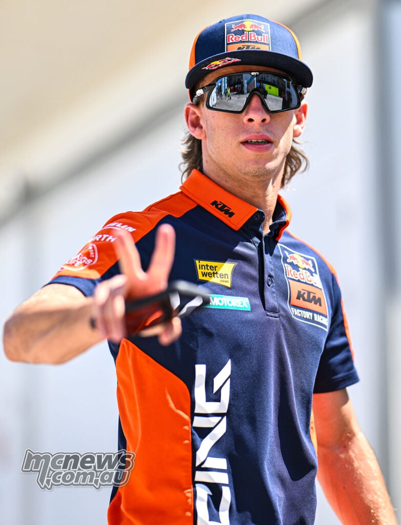 Pedro Acosta wears KTM team colours, a cap and mirrored sunglasses while making a peace sign at Mandalika.