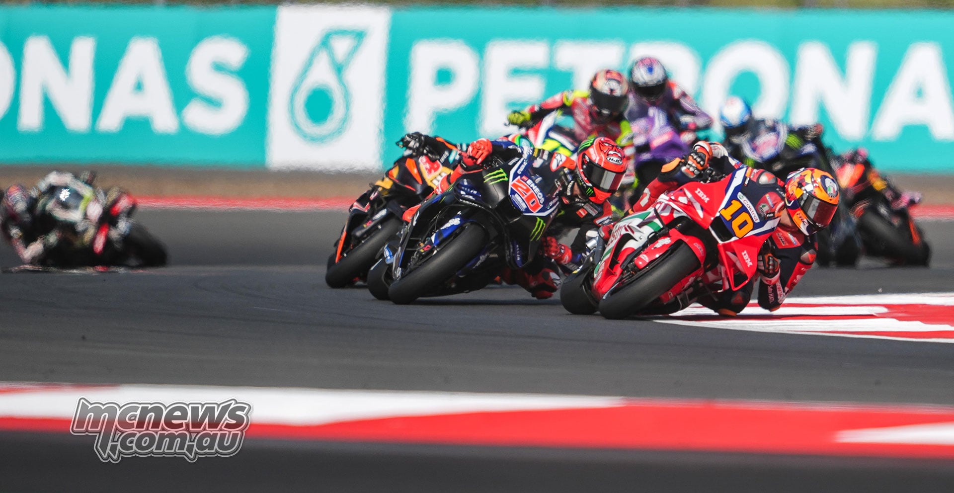 Luca Marini leads Fabio Quartararo and a line of riders through a right-hand corner.
