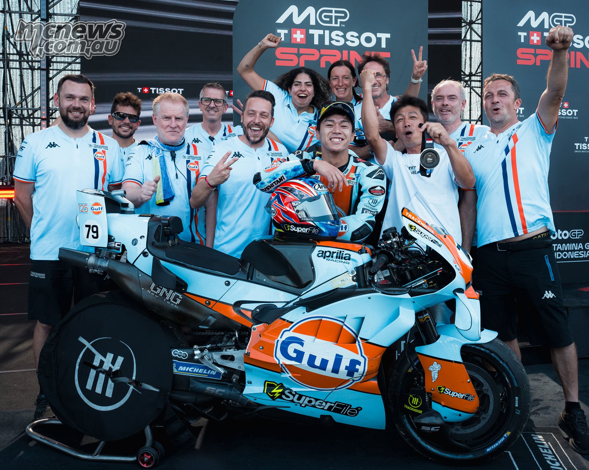Ai Ogura celebrates with the Trackhouse team behind his light blue and orange Aprilia.