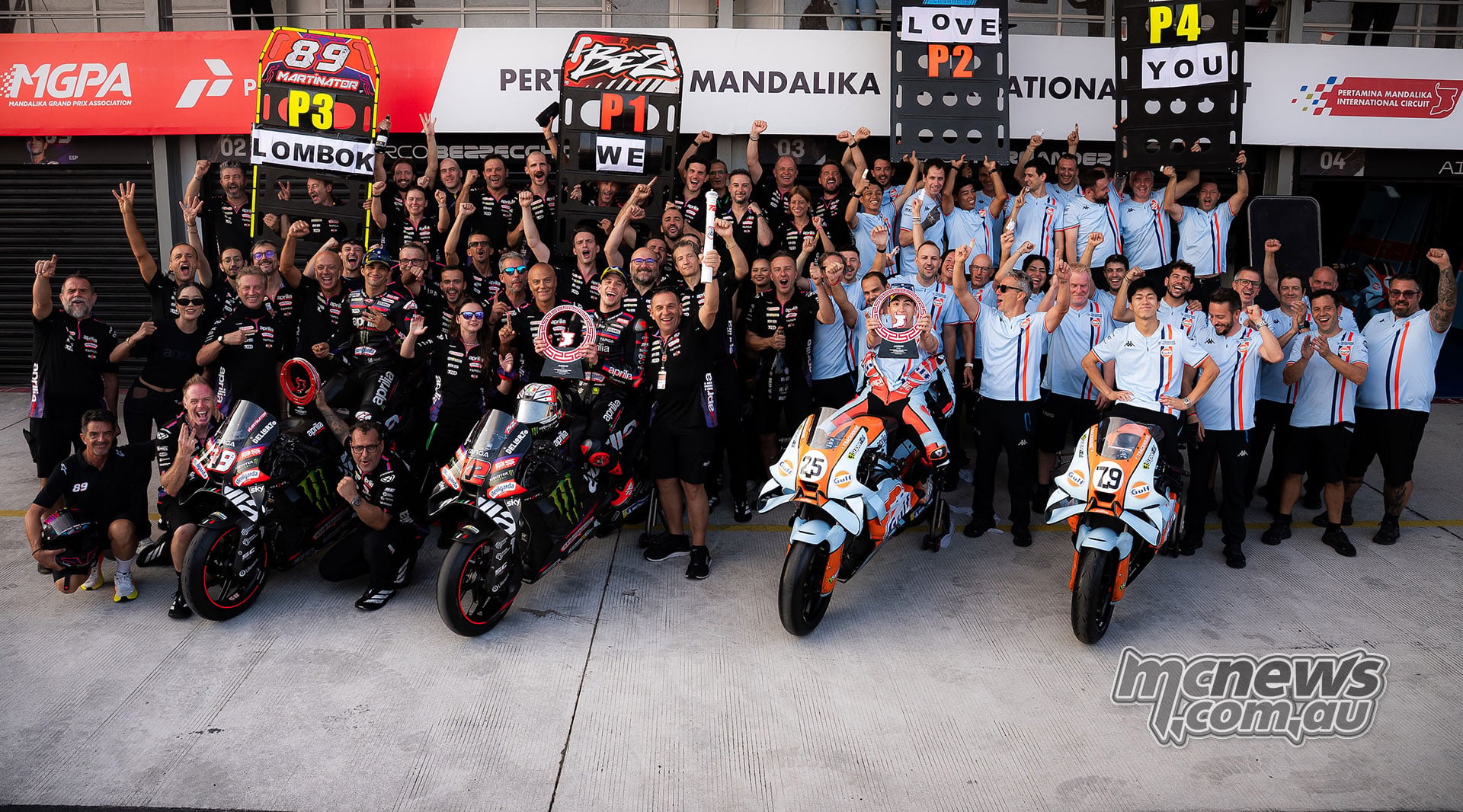Aprilia and Trackhouse riders and team members celebrating with four RS-GP motorcycles and position boards