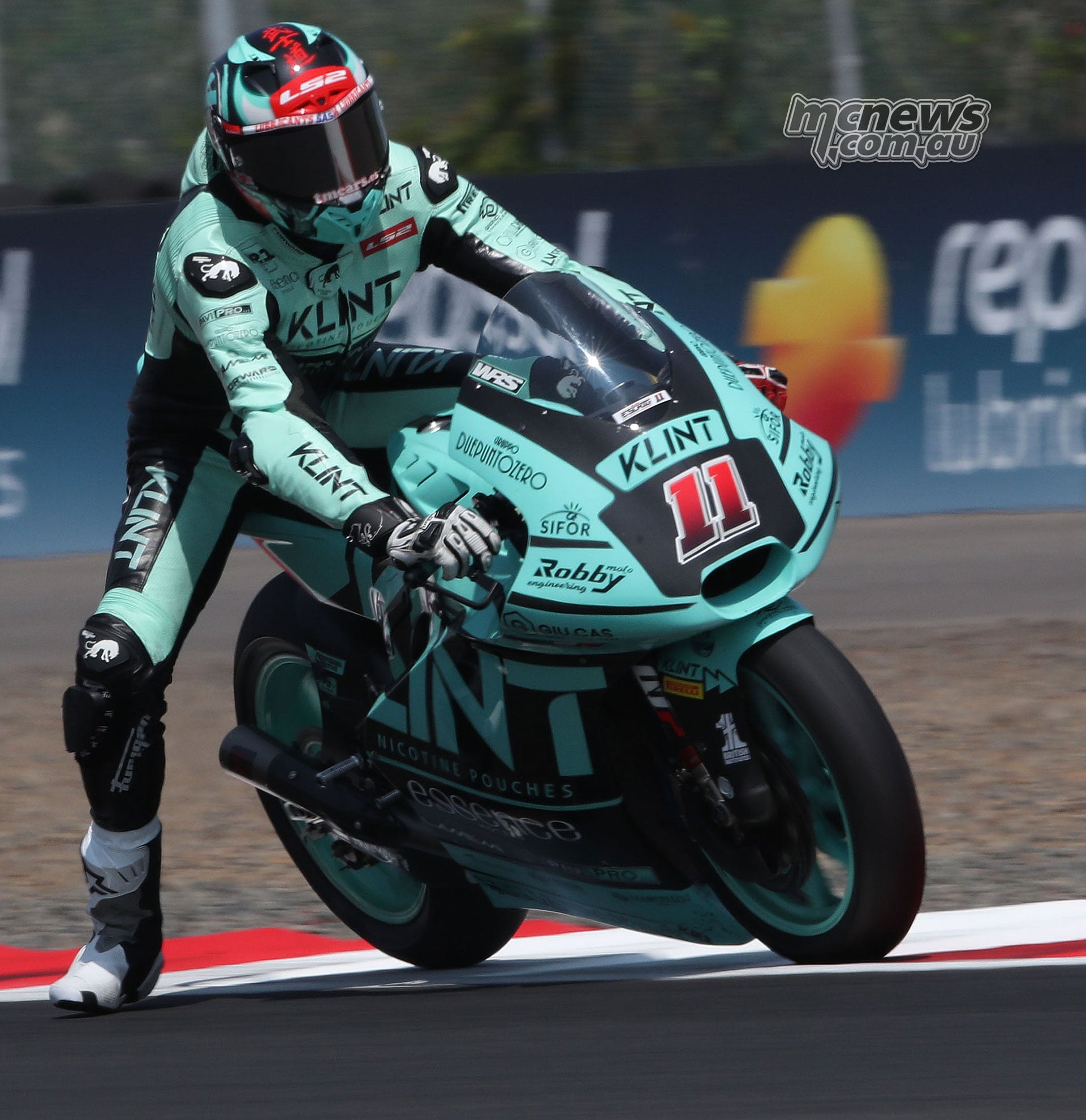 Alex Escrig sits upright on his number 11 Forward Moto2 machine with his left foot lowered towards the track.
