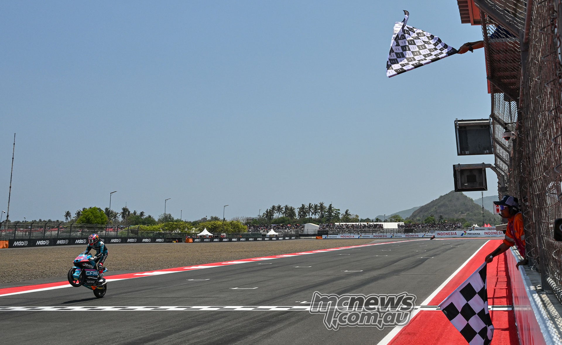 Maximo Quiles crosses the Mandalika finish line beneath the chequered flag on his CFMOTO Aspar machine.