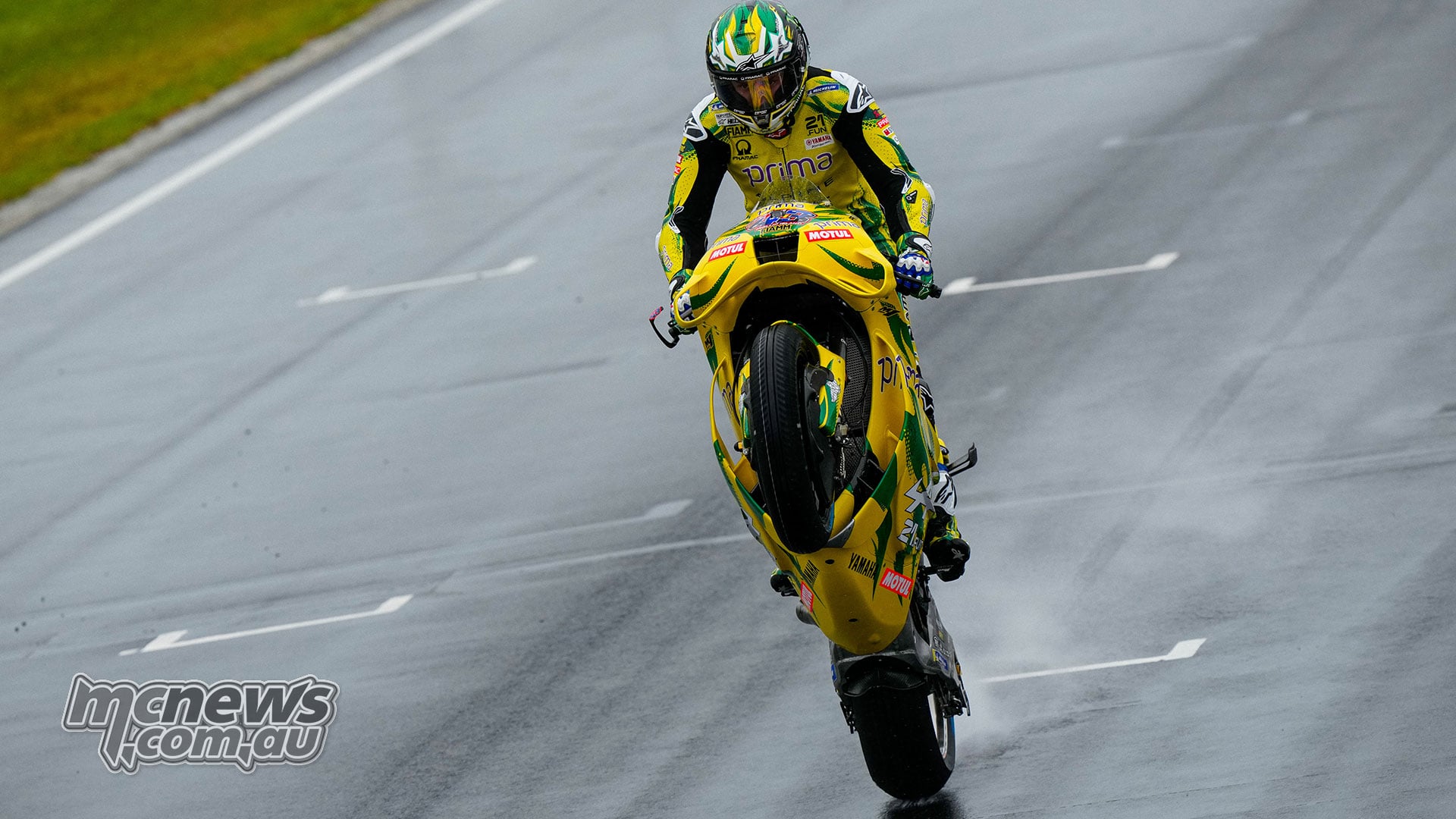 Jack Miller lifts the front wheel of his green-and-yellow Yamaha while riding along the wet Phillip Island main straight.