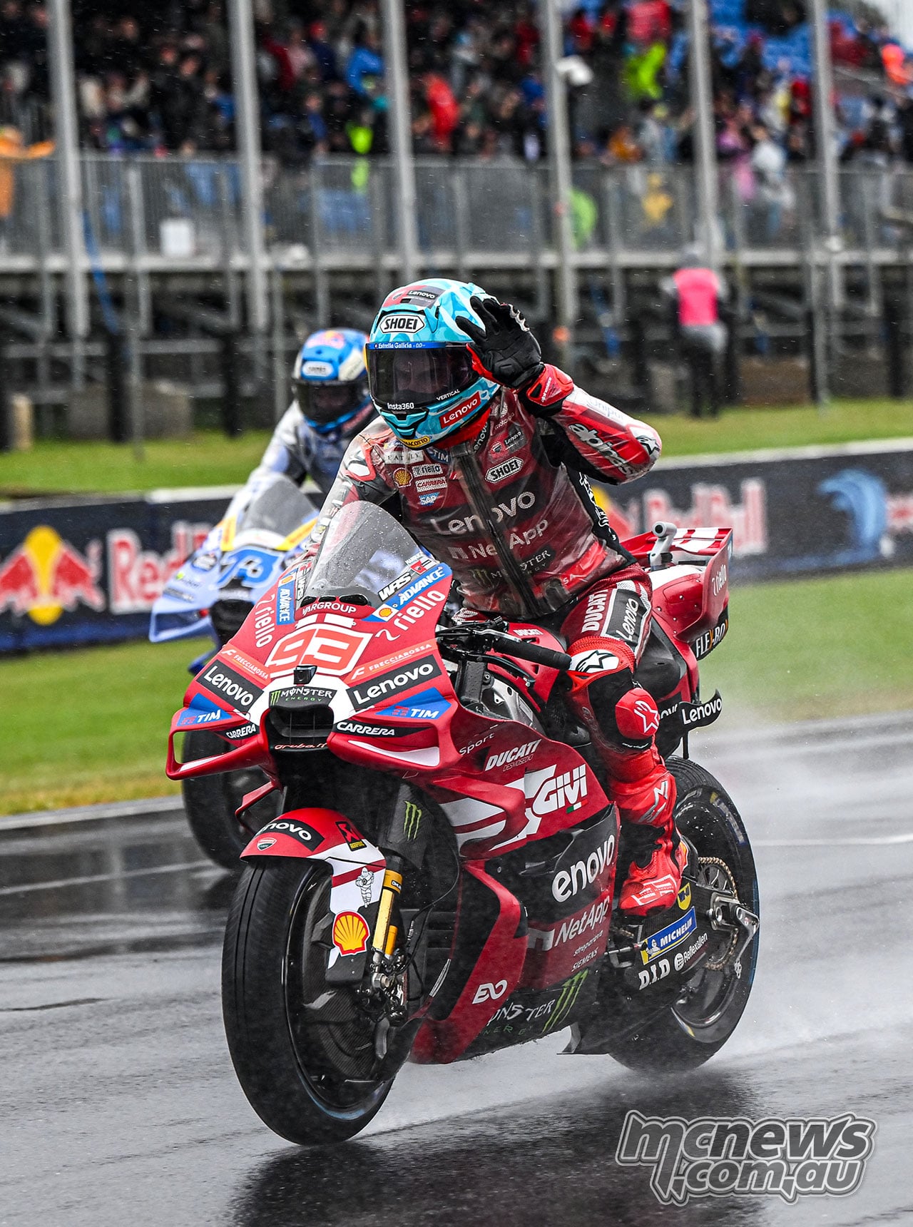 Marc Marquez rides his red number 93 Ducati ahead of Alex Marquez’s blue Gresini Ducati on the wet track.