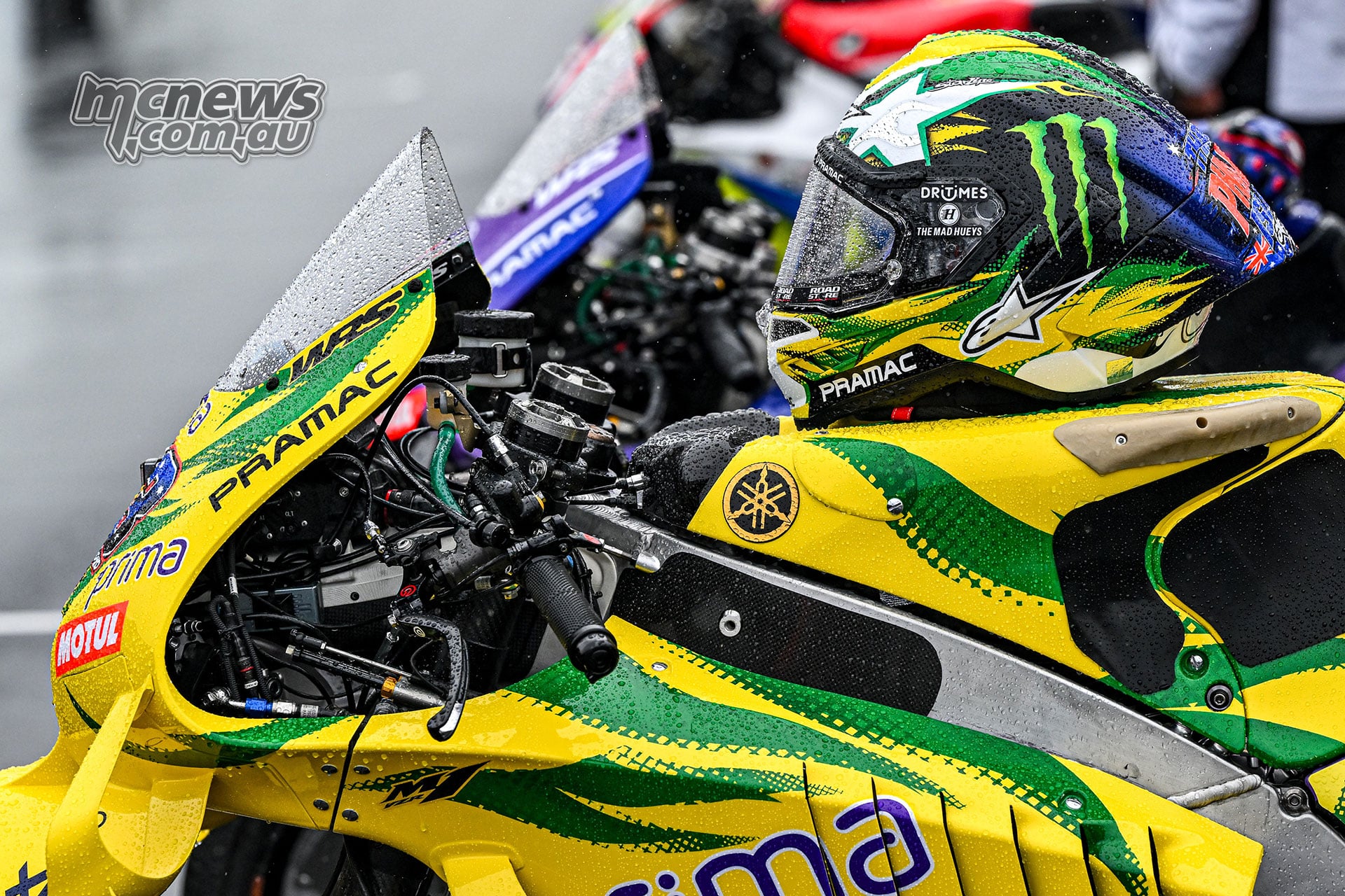 Jack Miller’s green-and-yellow helmet rests on his matching Pramac Yamaha, with raindrops on the bodywork.