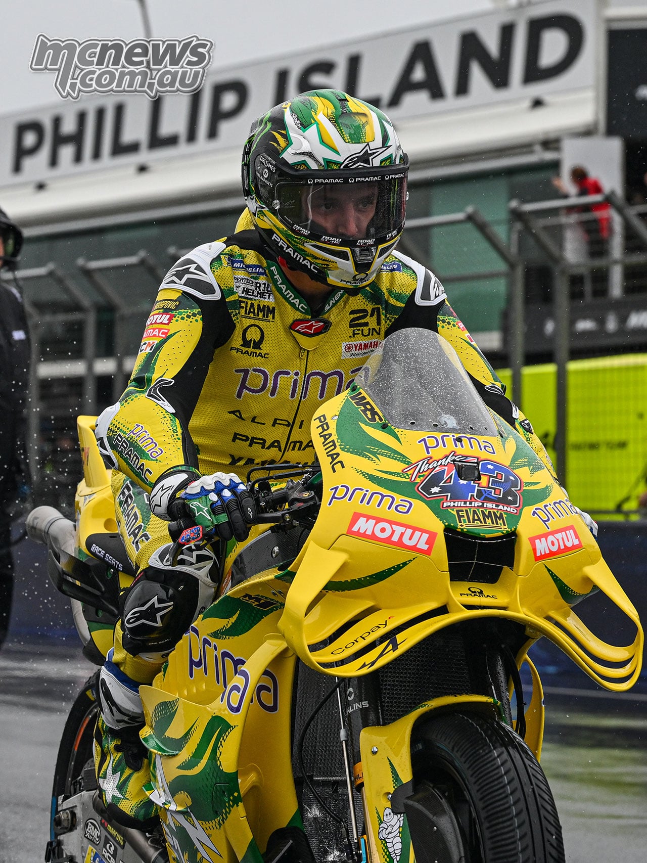 Jack Miller rides his green-and-yellow Pramac Yamaha beneath the Phillip Island sign beside the pit buildings.