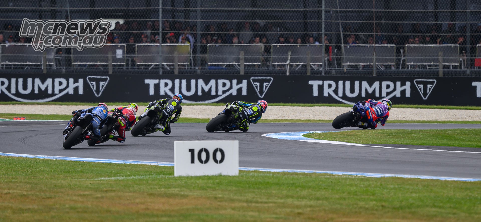Jack Miller leads a group of riders through a right-hand corner at Phillip Island, with spectators behind the safety fence.