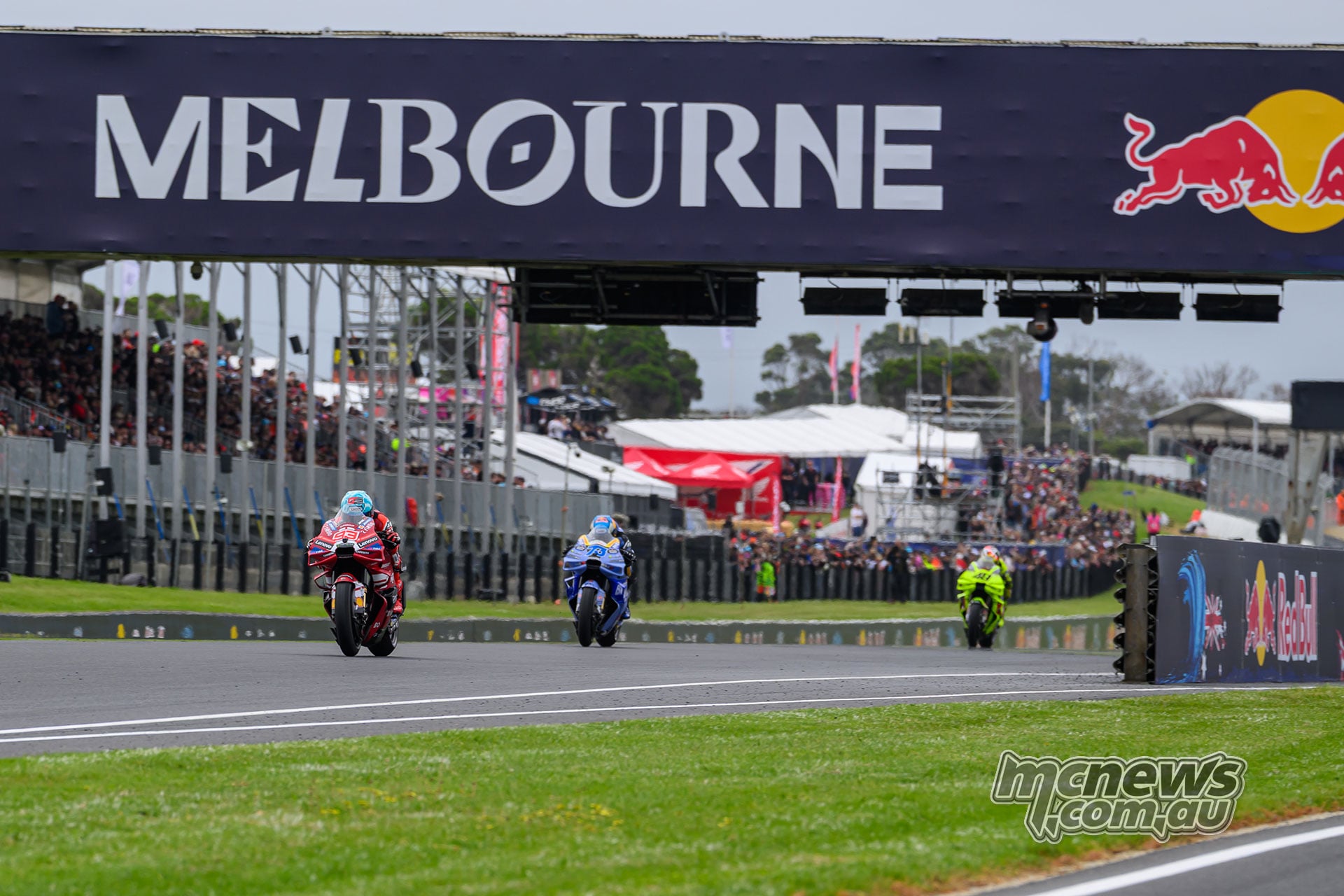 Marc Marquez leads Alex Marquez and Fabio Di Giannantonio along Phillip Island’s main straight beneath the Melbourne banner.