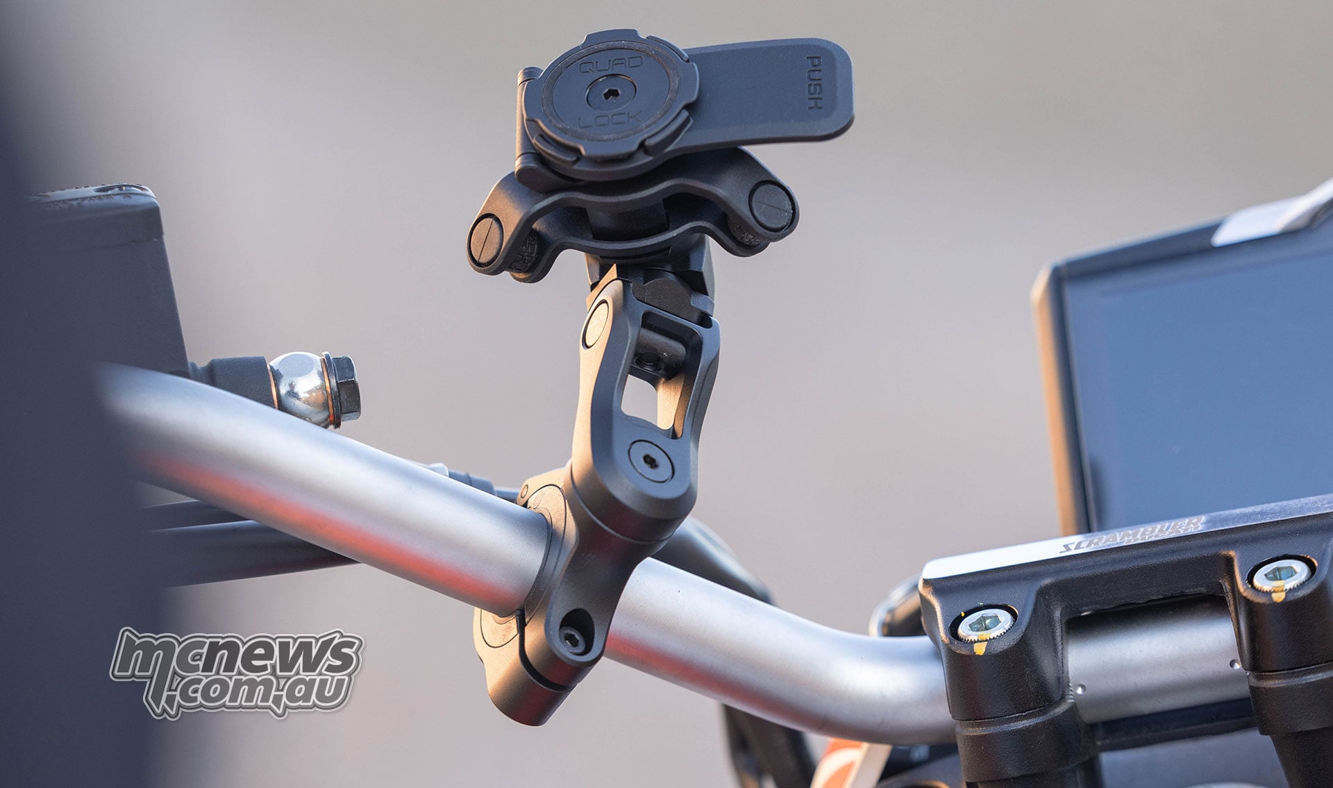 Close-up of the Quad Lock Handlebar Mount Pro Adjustable showing the pivoting aluminium arm, adjustable head, push-release lever and handlebar clamp