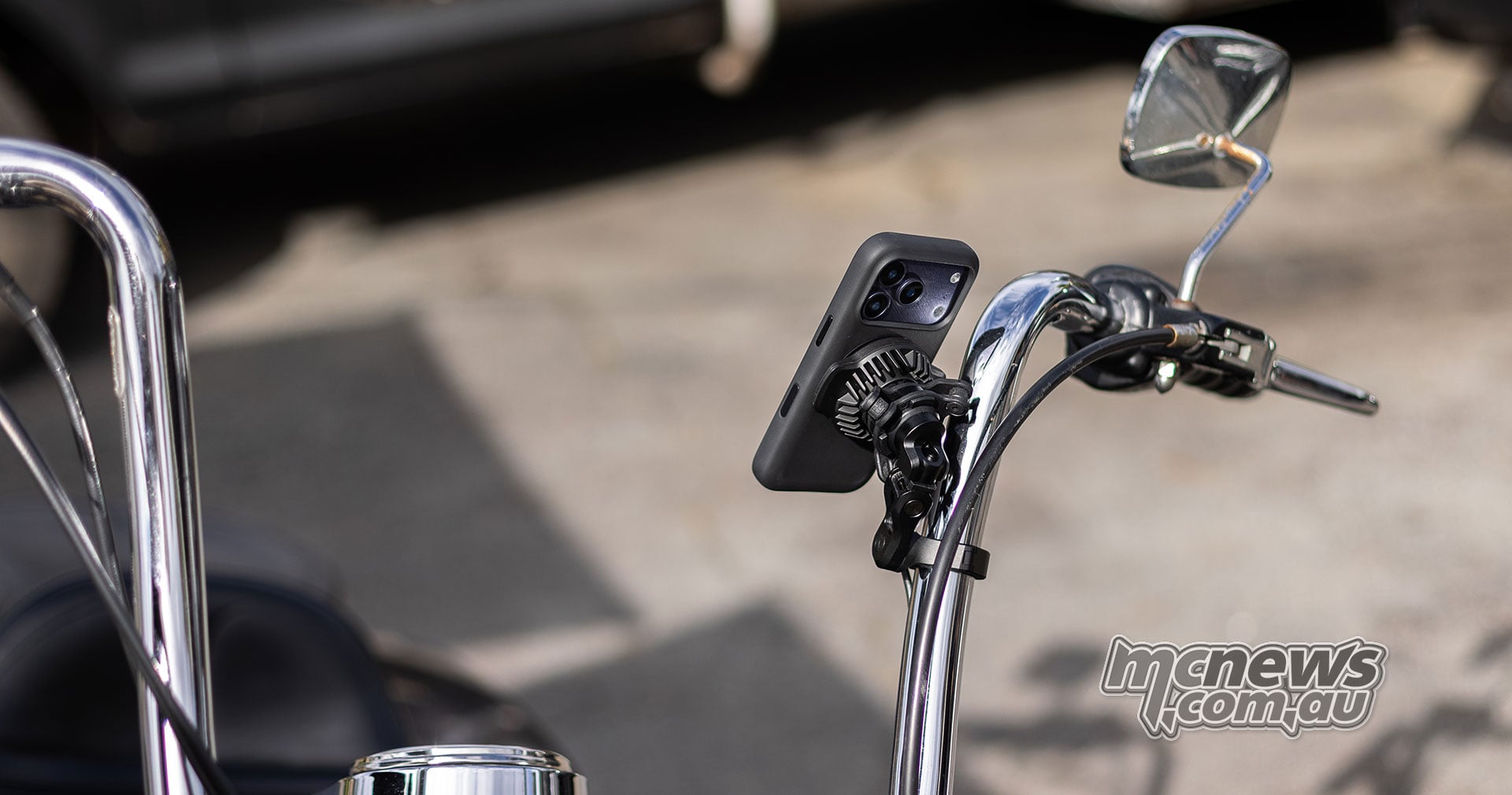 Rear view of a smartphone secured in a Quad Lock mount on the chrome handlebars of a cruiser motorcycle, illustrating the adjustable mounting position
