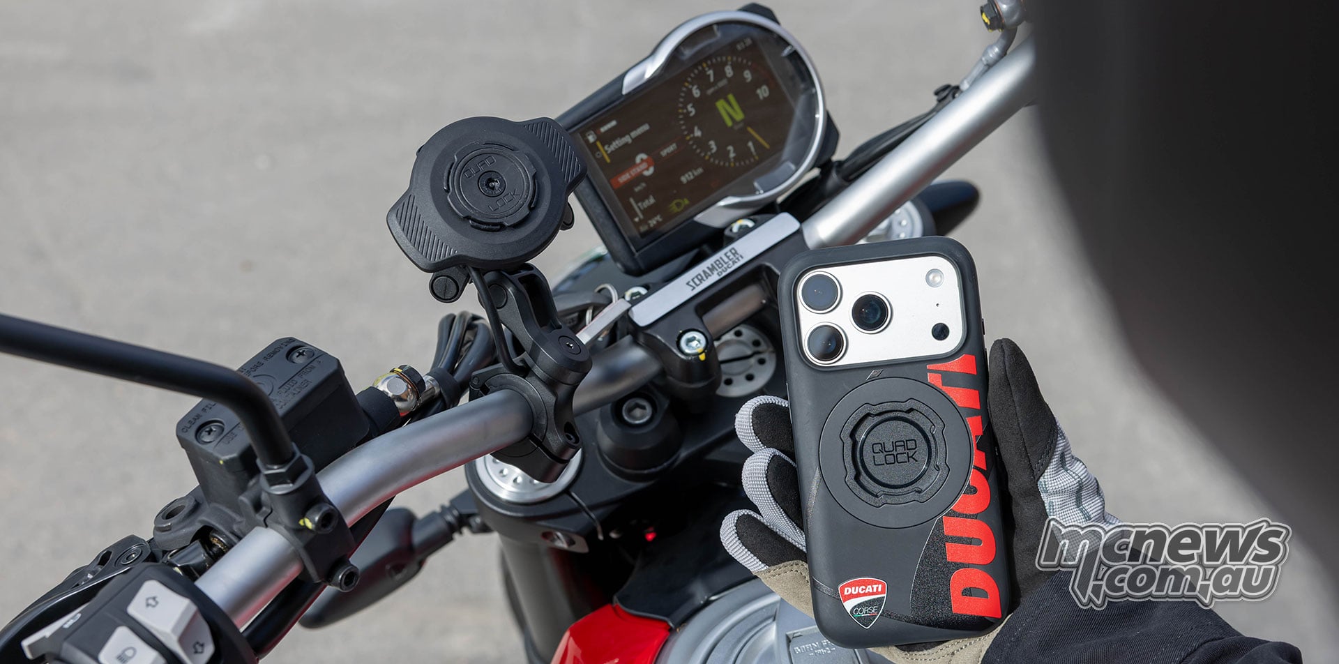 Ducati-branded Quad Lock smartphone case held beside the Handlebar Mount Pro Adjustable installed on a Ducati Scrambler motorcycle