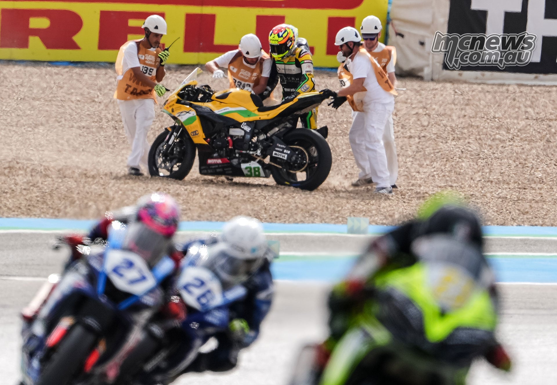 David Salvador and circuit marshals recover his yellow number 38 Team ProDina Kawasaki from the gravel trap at Jerez while other WorldSPB riders pass