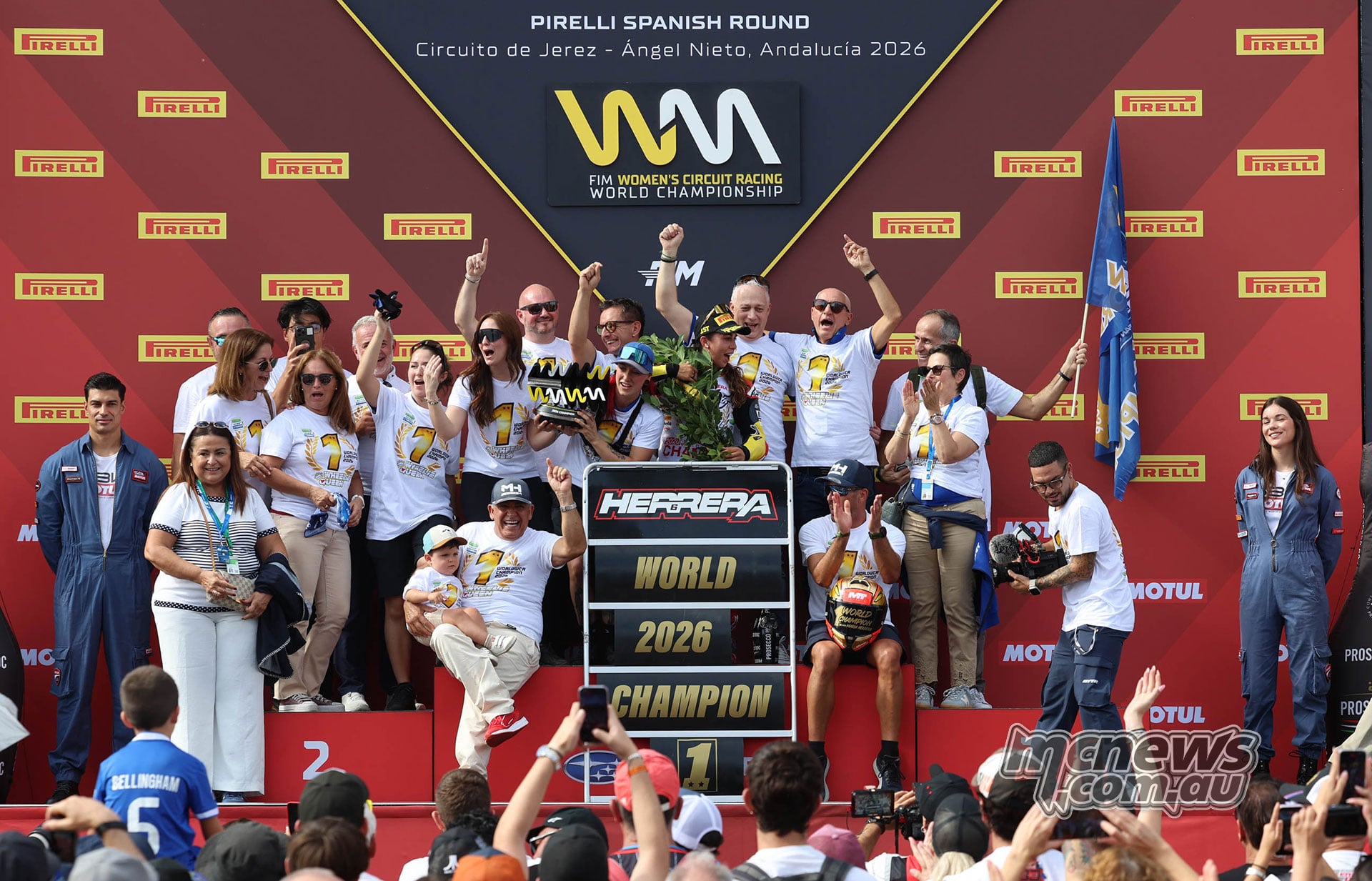 Maria Herrera celebrates the 2026 Women's Circuit Racing World Championship surrounded by cheering team members and supporters on the Jerez podium