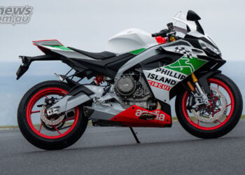 Right-side view of the Aprilia RS 660 Phillip Island Tribute, showing its white and green bodywork, circuit graphics and red wheels beside the coast.